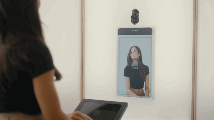 A woman taking a selfie with a mirror that has a built-in camera and a touchscreen control panel.